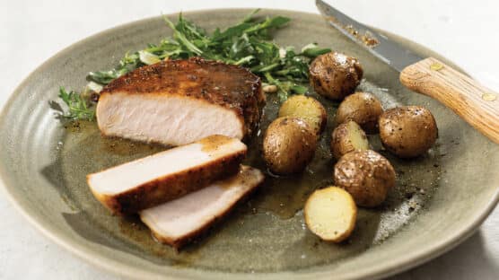 Mustard-Glazed Pork Chops with Steakhouse Potatoes and salad on a light green plate.