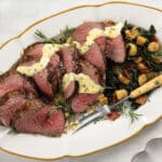 Chateaubriand cooked medium rare and sliced. Topped with dijon-hollandaise served with roasted parsnips and kale with bacon