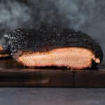 Smoked brisket with a dark bark on a cutting board