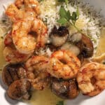 Grilled Shrimp and Mushrooms With Rice and White Wine & Lemon Butter Finishing Sauce on a white plate