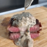 Spoon pouring mushroom cream sauce over steak