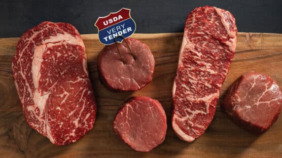 Cutting board with 5 raw steaks. From left to right: USDA Certified Tender Ribeye, 2 USDA Certified Very Tender Filet Mignon Steaks, USDA Certified Tender New York Strip and Top Sirloin.