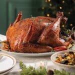 Holiday table set with sour cherry-cabernet glazed turkey, roasted root vegetables, and glass of Omaha Steaks 1917 cabernet wine.