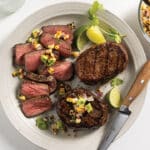 White plate with 3 grilled top sirloin filet steaks with corn and avocado salsa