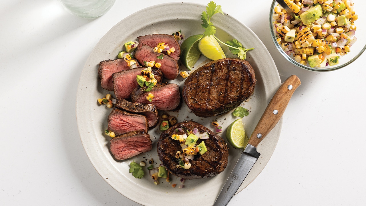 White plate with 3 grilled top sirloin filet steaks with corn and avocado salsa