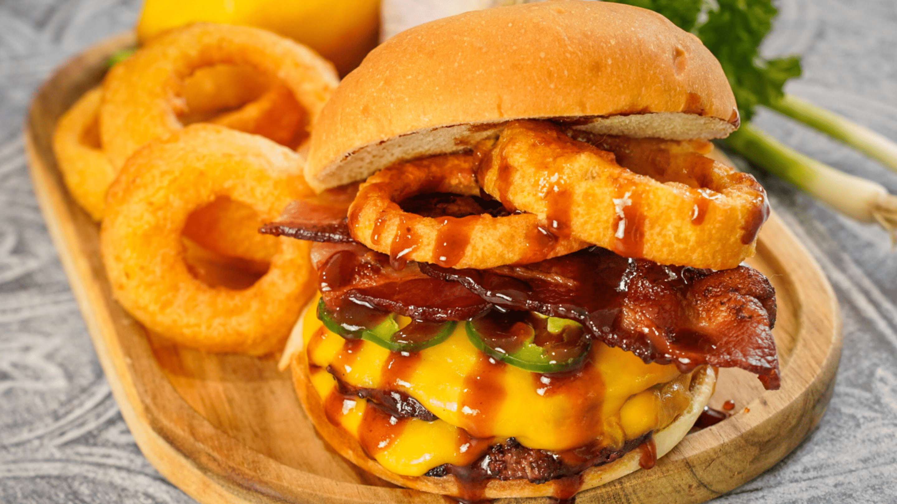 Platter with double smash burger with American cheese, Jalapeños, sliced bacon, cooked onion rings and coated in cowboy butter. Served with a side of onion rings