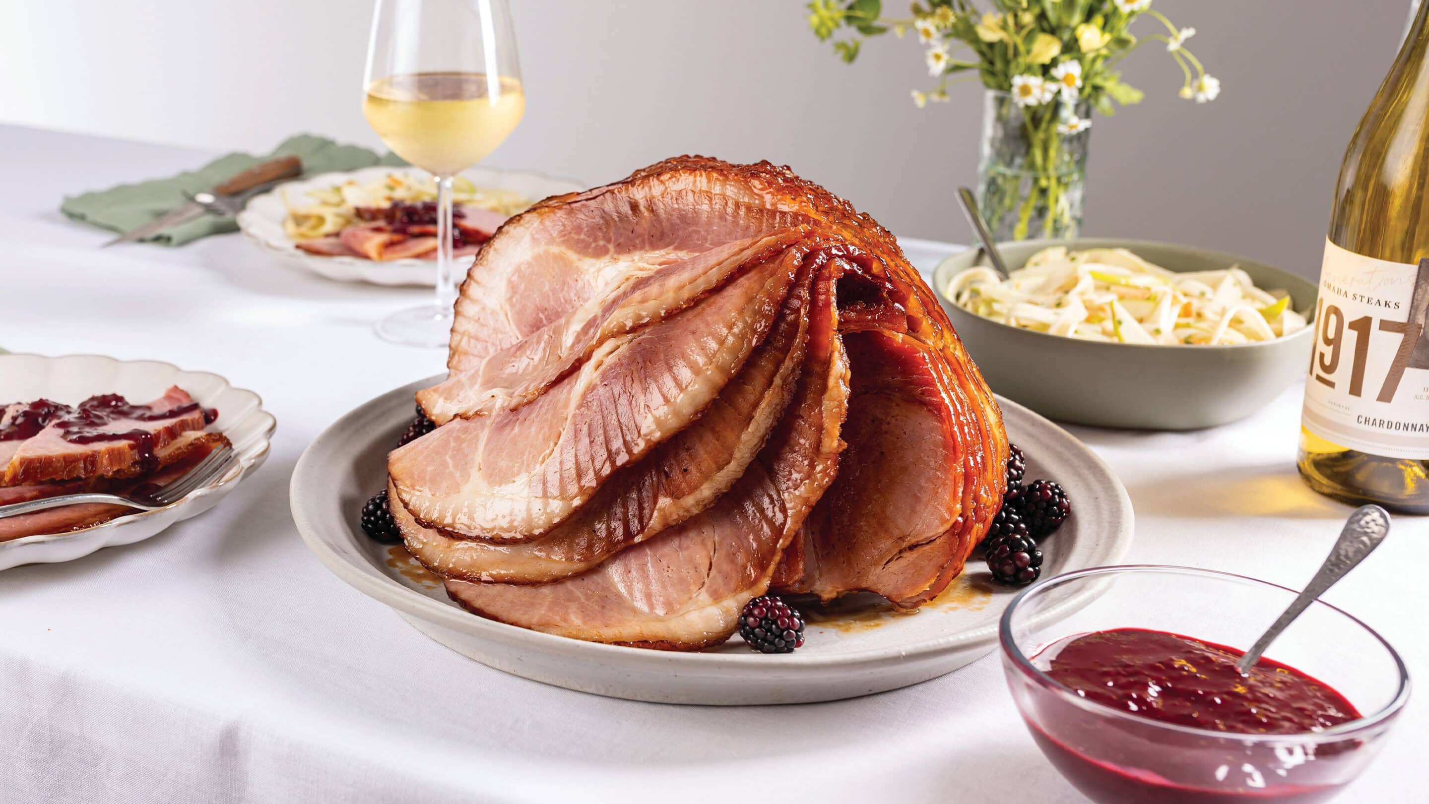Elegant table with a blackberry bourbon glazed spiral sliced ham and apple-fennel slaw.